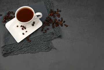 Tasse Kaffee und Kaffeebohnen auf einem grauen Steinhintergrund mit Textfreiraum.