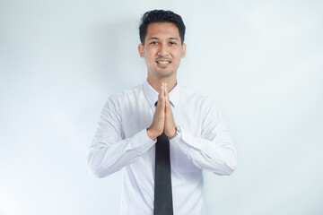 Adult Asian businessman smiling friendly while greeting someone.  namaste greeting hands. Indonesian man on white background.