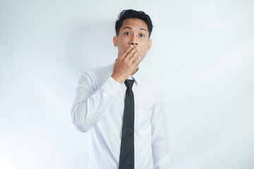 Headshot of terrified fearful young Asian businessman covering mouth and looking at camera with...