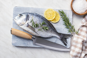 Fresh sea bream fish on cutting board on kitchen table. Top view. - 791402441