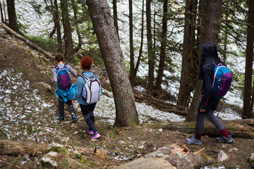 Tourist women with backpacks hiking on a trail in the mountains