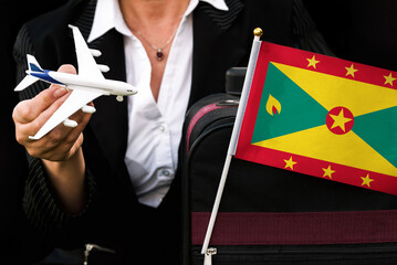 business woman holds toy plane travel bag and flag of Grenada