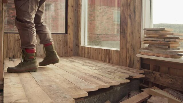 Man Fastening Wooden Flooring Inside Greenhouse. static shot