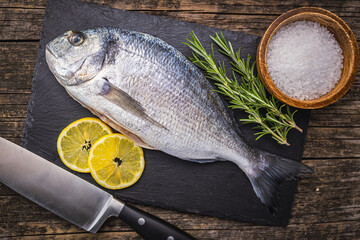 Fresh sea bream fish on cutting board on wooden table. Top view. - 791404411