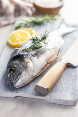 Fresh sea bream fish on cutting board on kitchen table. - 791404895