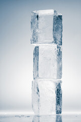 Cubes of natural textured clear ice on a white reflective surface. Ice background.