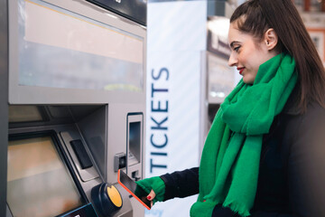 Smiling woman buying ticket through smart phone at train station