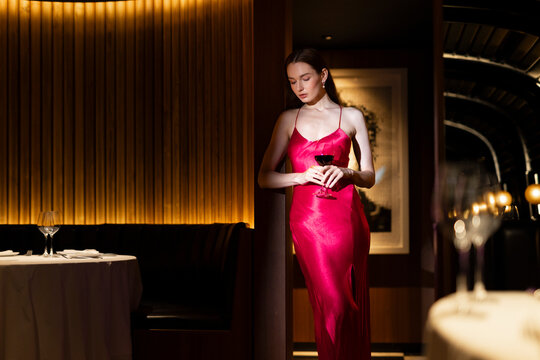 Beautiful young woman holding glass of wine at expensive club