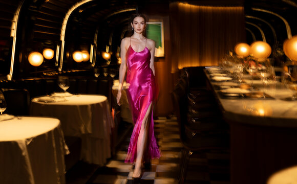 Beautiful woman in glamorous gown walking at illuminated club