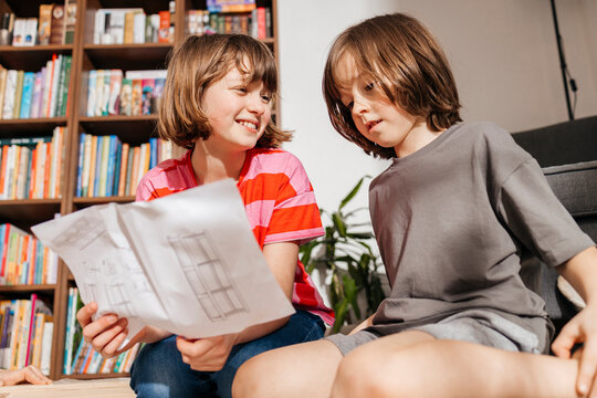Smiling girl with boy reading instructions for assembling furniture at home