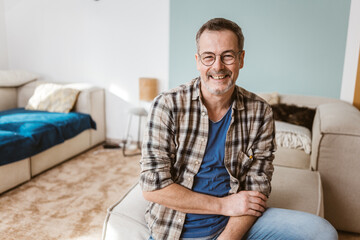Smiling Senior Man with Glasses Relaxing on Sofa in Living Room - 791410285