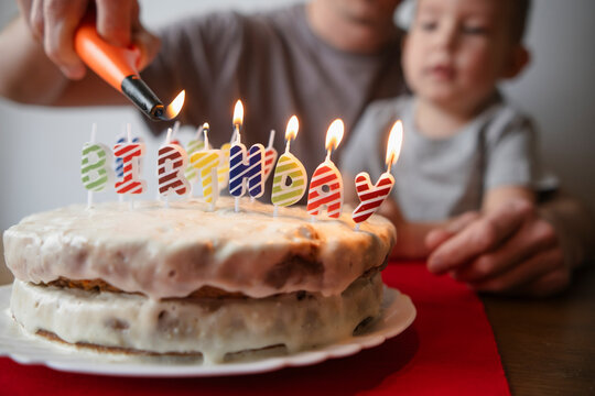 Father lighting birthday cake of son at home