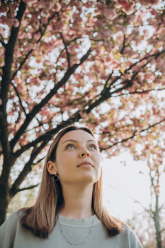 Thoughtful woman under cherry blossoms at park