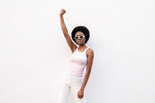 Young woman wearing sunglasses and protesting against white background