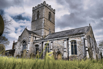 HDR Small Christian parish church in the English countryside. Stormy clouds and grave stones.