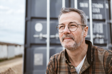 Middle-aged Man Pondering Outdoors Near a Gray Container