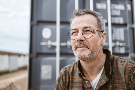 Middle-aged Man Pondering Outdoors Near a Gray Container