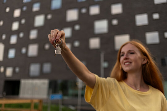 Happy woman holding house keys in front of building
