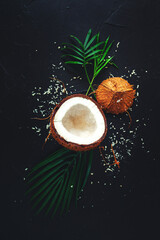 Broken coconut and palm leaves on a black background.