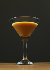 Liqueur in a martini glass. Cinnamon-colored alcoholic drink. Alcoholism, drunkenness in a bar. The sweet drink has a low alcohol content