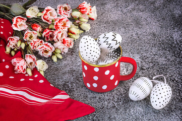 Easter composition with white and black polka dot eggs in a red and white polka dot cup, eustoma...