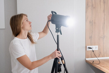 woman video maker at work, working on content making, using and controlling video light strobe