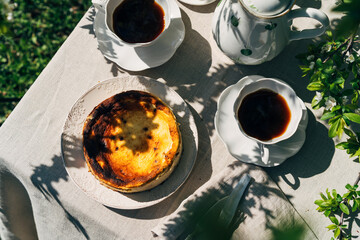 Breakfast table in summer garden. Basque Cheesecake and coffee in the countryside