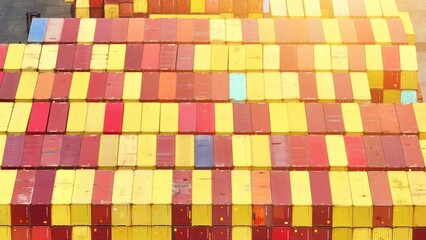 An aerial view unveils a bustling shipping yard, a symphony of stacked containers, vibrant hues, and industrious trucks navigating between rows with precision.
