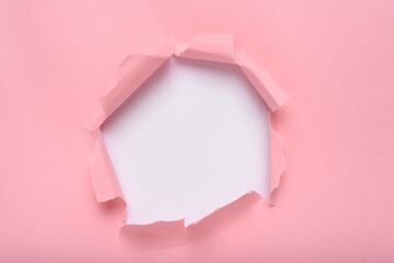 Torn hole in pink paper revealing white background, space for text.