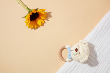 Top view photography with linen towel, toy in animal shape and sunflower flat lay on light pink background. Photography for designing advertise pics products of baby