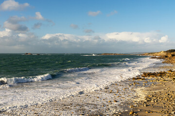 Vague éclatante sur galets, écume blanche éphémère, une image emblématique du littoral breton dans le Finistère nord.