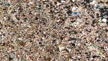 A tightly packed waste field scattered with items of assorted colors, emphasizing the intricate challenge and vast scale of waste management. Landfill background. Aerial view.
