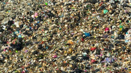 A detailed view of a landfill, showing a vast amount of mixed refuse with a variety of colors and...