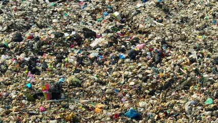 A drone surveys a sea of trash, a mosaic of hues and materials, sprawling across a vast landfill. Colors blend in chaos, revealing our society's discarded remnants in this waste disposal expanse.
