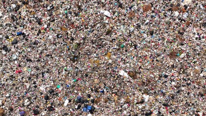 An expanse of densely packed garbage, with a multitude of colors and materials mixed together, indicative of a large waste disposal site. Landfill background. Aerial view.
