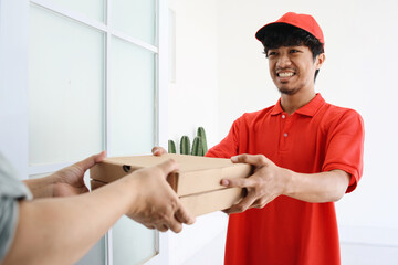 Delivery man in red uniform deliver two boxes of pizza to customer. Fast food delivery concept.