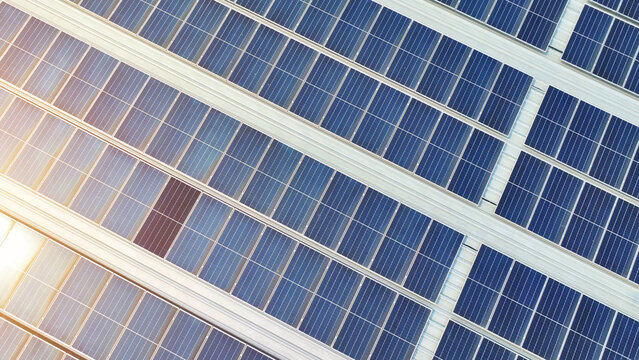 Green innovation: Neatly aligned blue solar panels cover the rooftop, symbolizing the building's steadfast commitment to renewable energy. Solar panels background.
