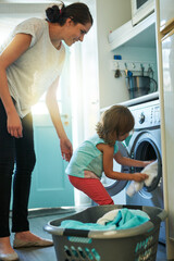 Help, laundry and mom with kid in home for chores, teaching and learning housekeeping routine. Washing machine, mother and daughter cleaning clothes together with support, care and child development.