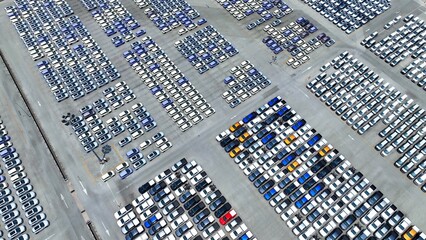 An expansive parking lot sprawls below, a sea of neatly aligned cars gleaming under the sunlight, a...