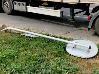 overturned traffic sign after a traffic accident. lies on the ground on concrete pavement behind a...