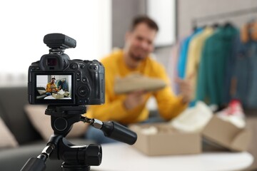 Fashion blogger showing shoe while recording video at home, focus on camera