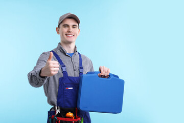 Professional repairman with tool box showing thumbs up on light blue background. Space for text
