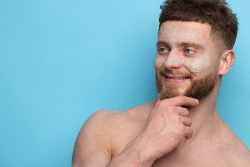 Fototapeta premium Handsome man with facial mask on his face against light blue background, space for text