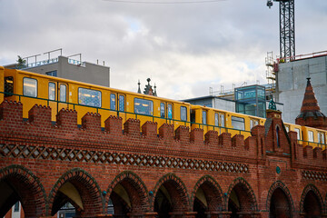 Yellow train travels across a historic red brick bridge in Berlin