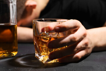 Alcohol addiction. Man with glass of whiskey at dark textured table, selective focus