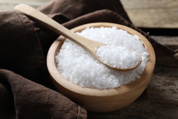 Fototapeta na wymiar Organic salt in bowl and spoon on wooden table, closeup