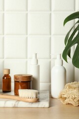 Obraz na płótnie Canvas Different bath accessories and personal care products on wooden table near white tiled wall
