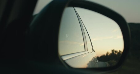 Mirror view sunset sky car drives on shaky road evening close up