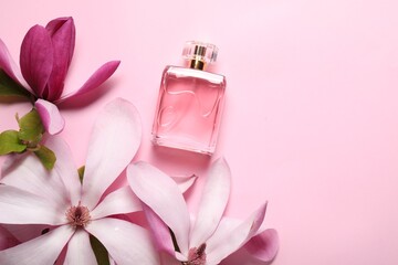 Beautiful magnolia flowers and bottle of perfume on pink background, flat lay. Space for text
