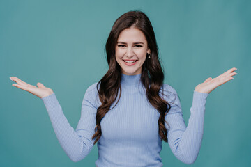 Cheerful woman in blue, hands out, aqua background